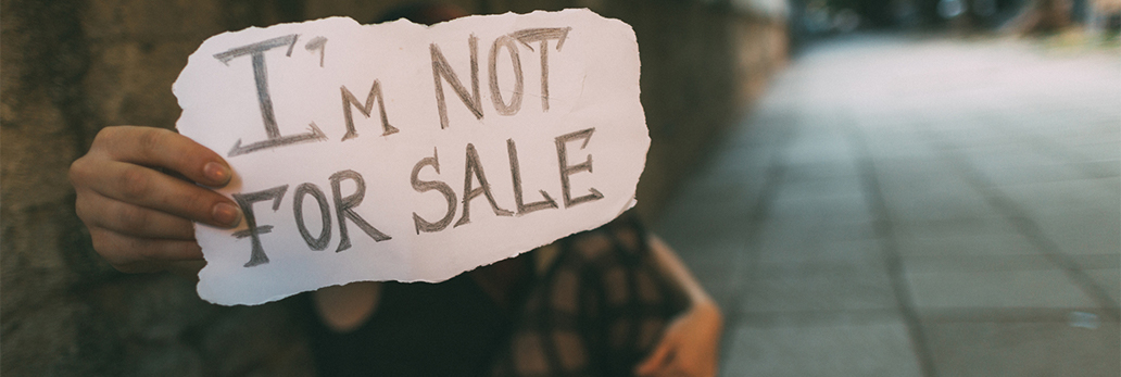 A girl holds her hand forward, on which is written the words "I'm not for sale."