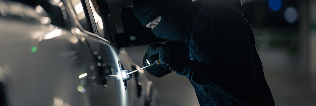 A male is breaking into a vehicle using a tool