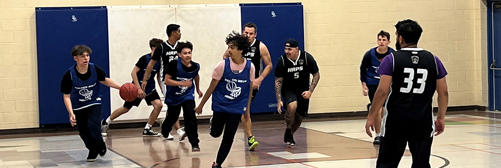 Youth participating in a basketball game against HRPS officers