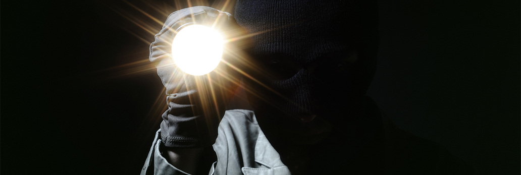 A burglar holds a flashlight