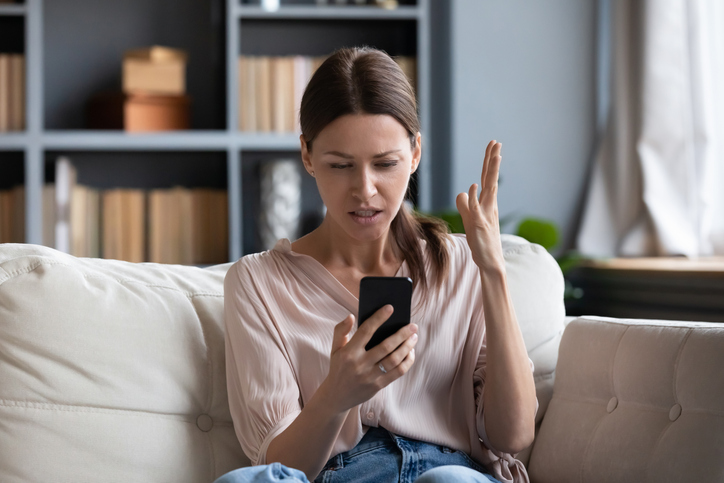 A woman stares at her cell phone in frustration