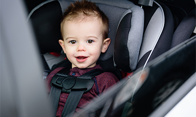 A toddler sits in a child safety seat in a vehicle