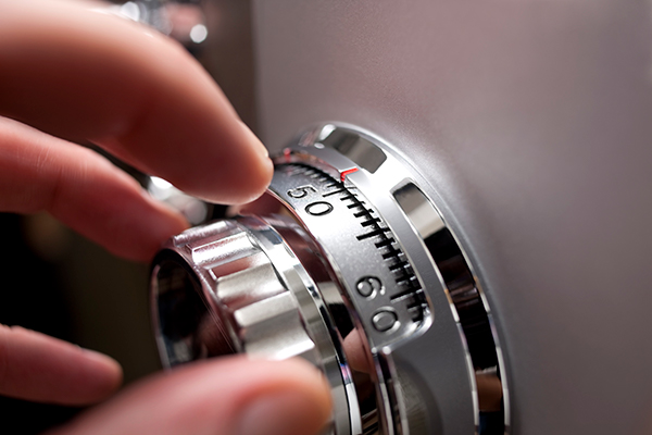 A hand turns a dial on a house safe