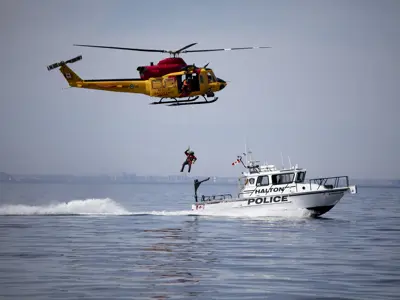 RCAF helicopter lowering a rescuer onto HRPS marine boat