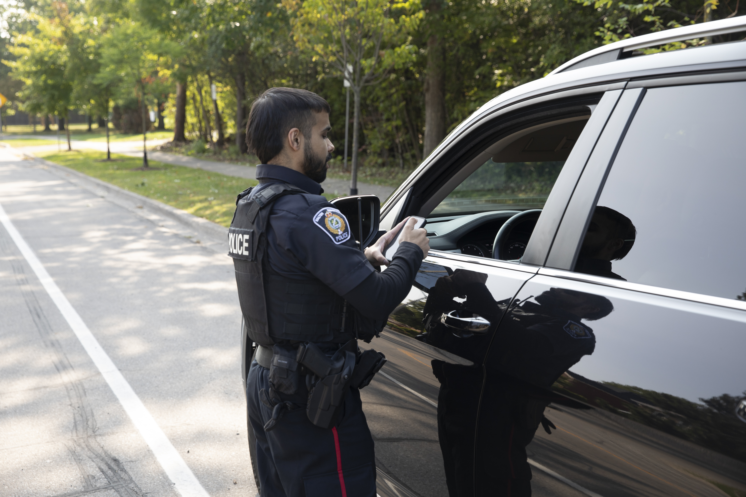 HRPS Officer at a cruiser window on his phone
